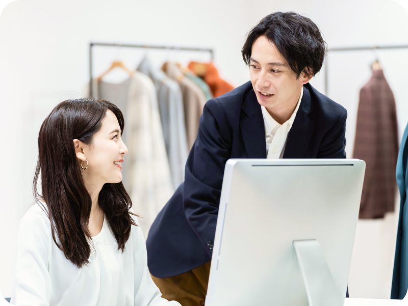 パソコンを使いながら打ち合わせをするアパレルスタッフ