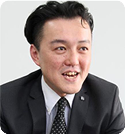 木目調の背景で笑顔の男性講師のプロフィール写真